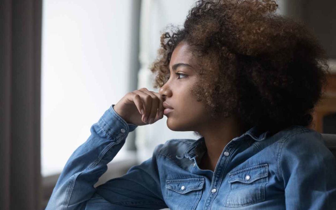 Close up side profile view face of a woman sitting on the sofa at home looking into the distance