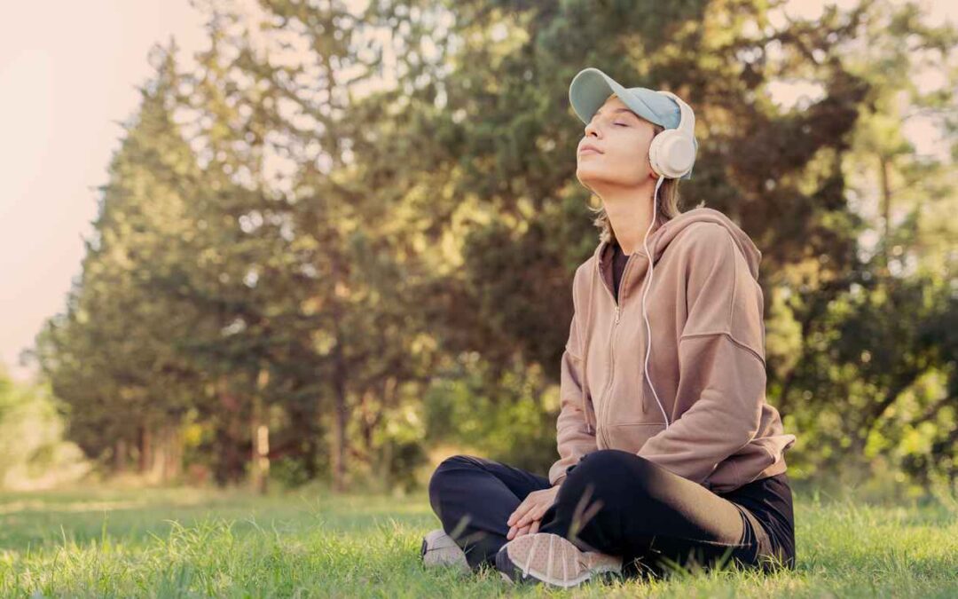 Woman sitting on the ground listening to music with headphones in the nature
